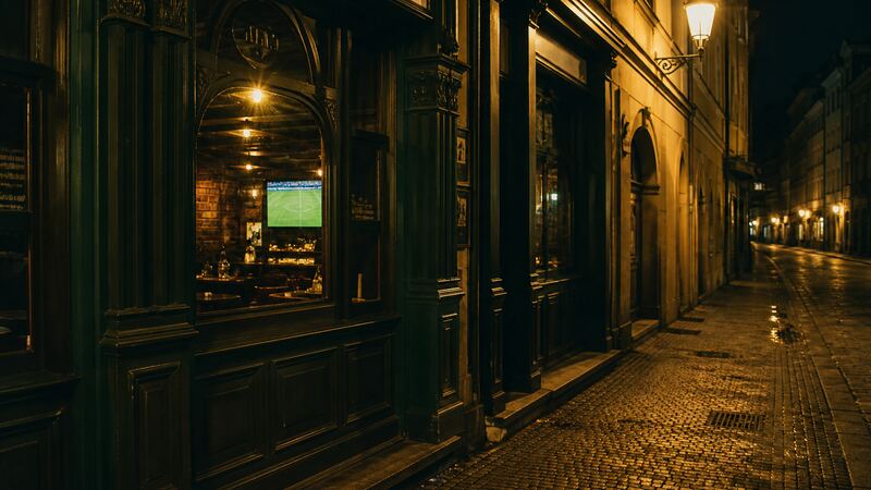 Večerní ulice u kamenného sportbaru, prázdný chodník a světlo z oken